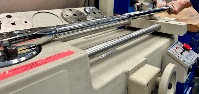 Metrólogo operando banco de calibración de par torsional para verificar la magnitud de Newton-metro en un transductor de referencia.